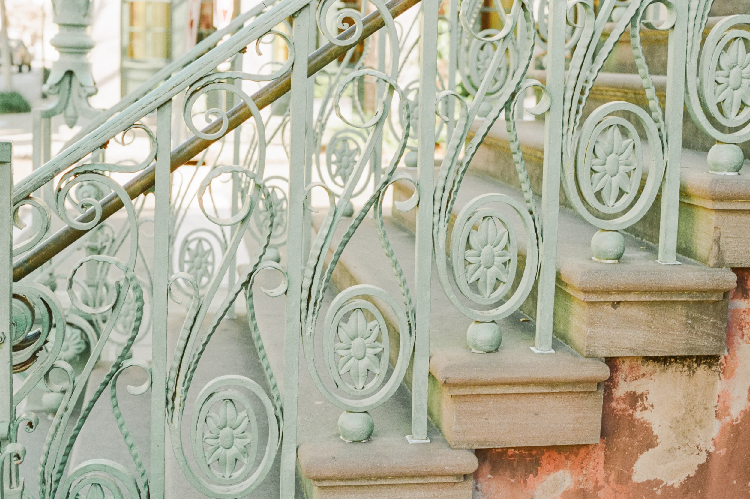 Close-up of ornate wrought-iron staircase, painted in a soft pastel green.