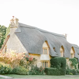 Charming stone cottage with a thatched roof and flower-filled garden.