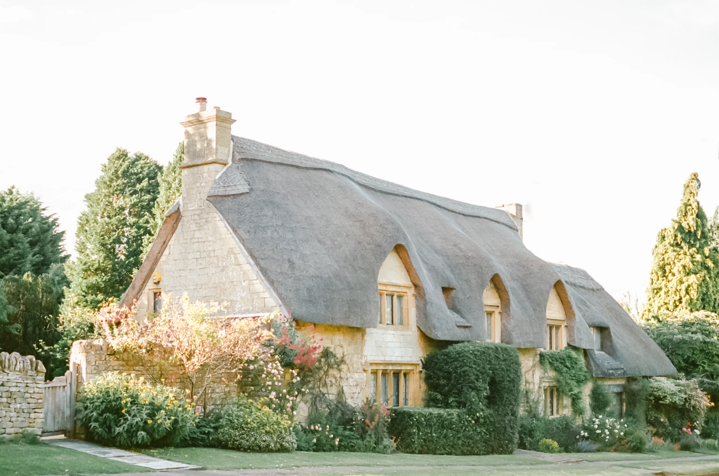 Charming stone cottage with a thatched roof and flower-filled garden.