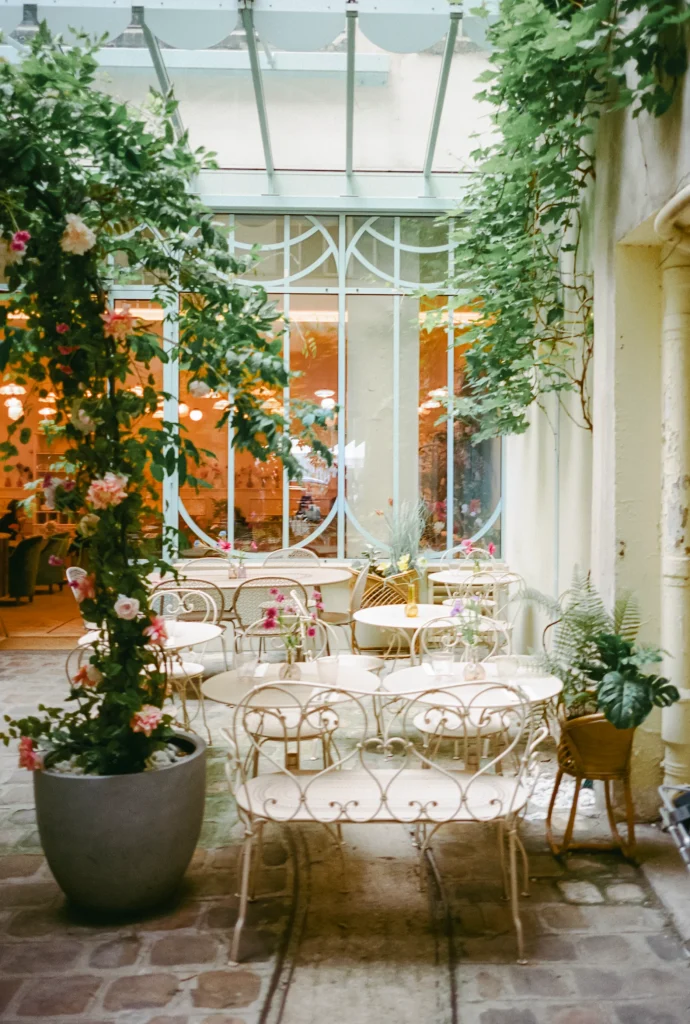 Cozy courtyard café filled with greenery and iron chairs.