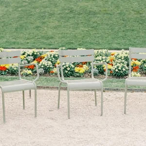 Empty garden chairs by flower bed – peaceful France garden photography, minimalist wall decor.