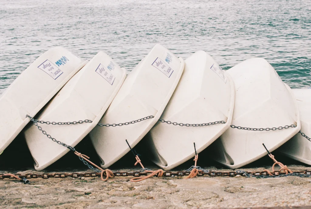 Row of white boats stacked by the shoreline.