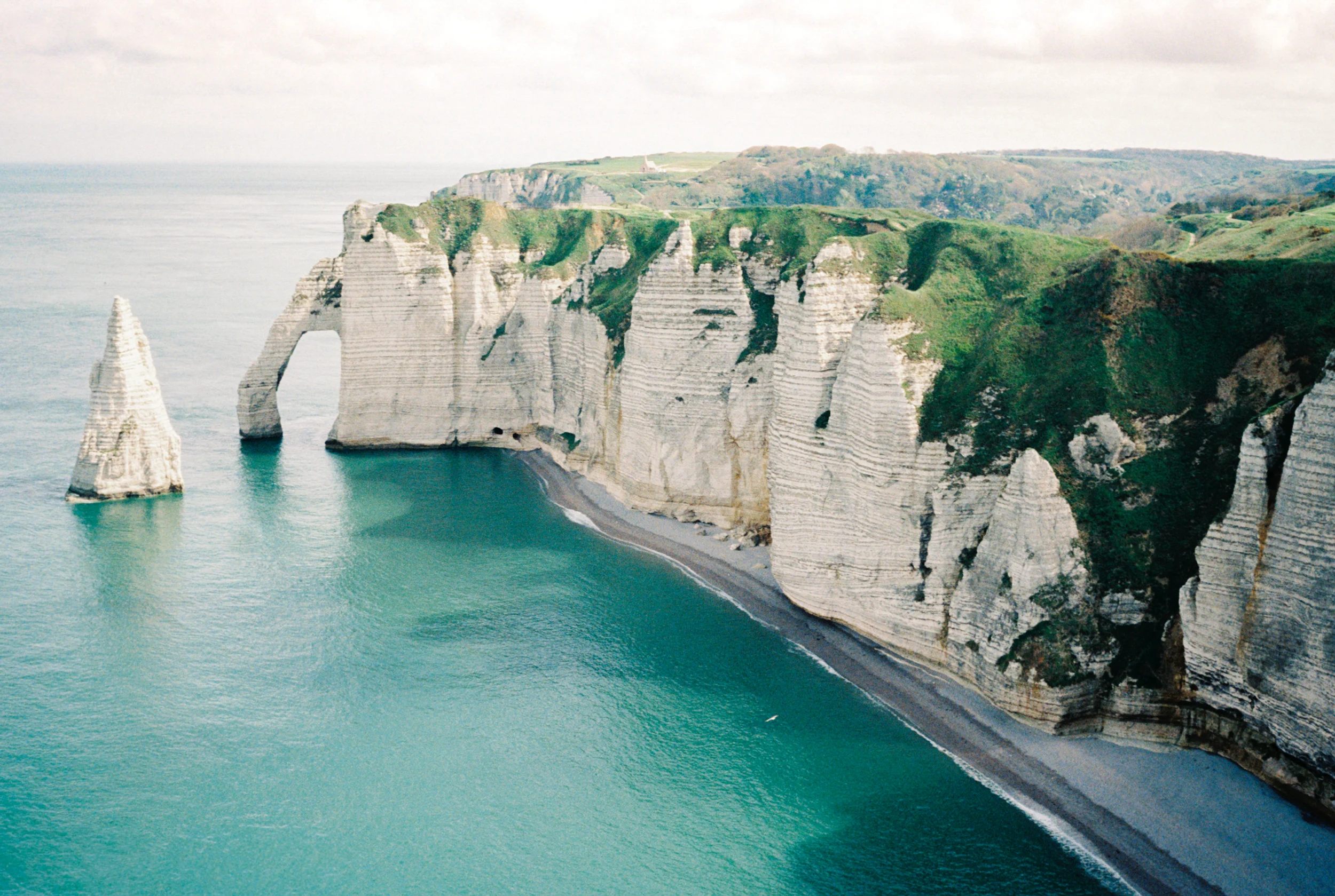 Panoramic coastal cliffs with turquoise water.