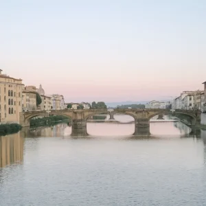 Ponte Vecchio bridge over the Arno River in Florence during golden hour.