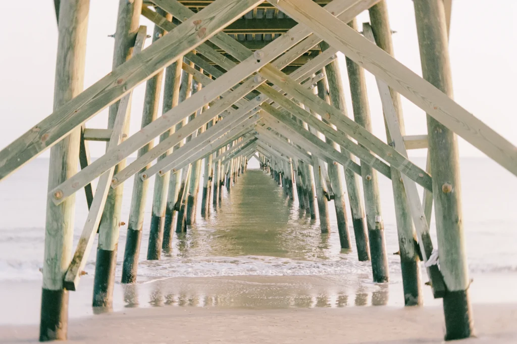 Wooden walkway through beach dunes – coastal travel photography, serene art print.