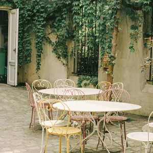 Quiet café courtyard with vintage metal chairs and climbing ivy.