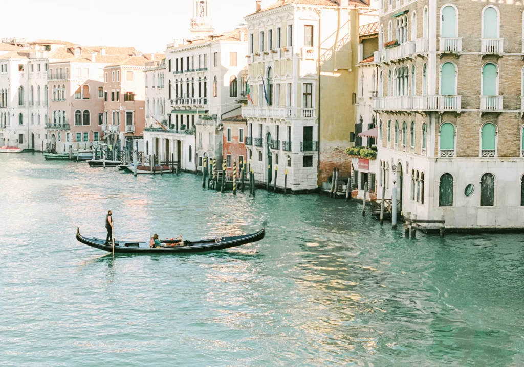 Gondola gliding through a canal in Venice, lined with pastel buildings.