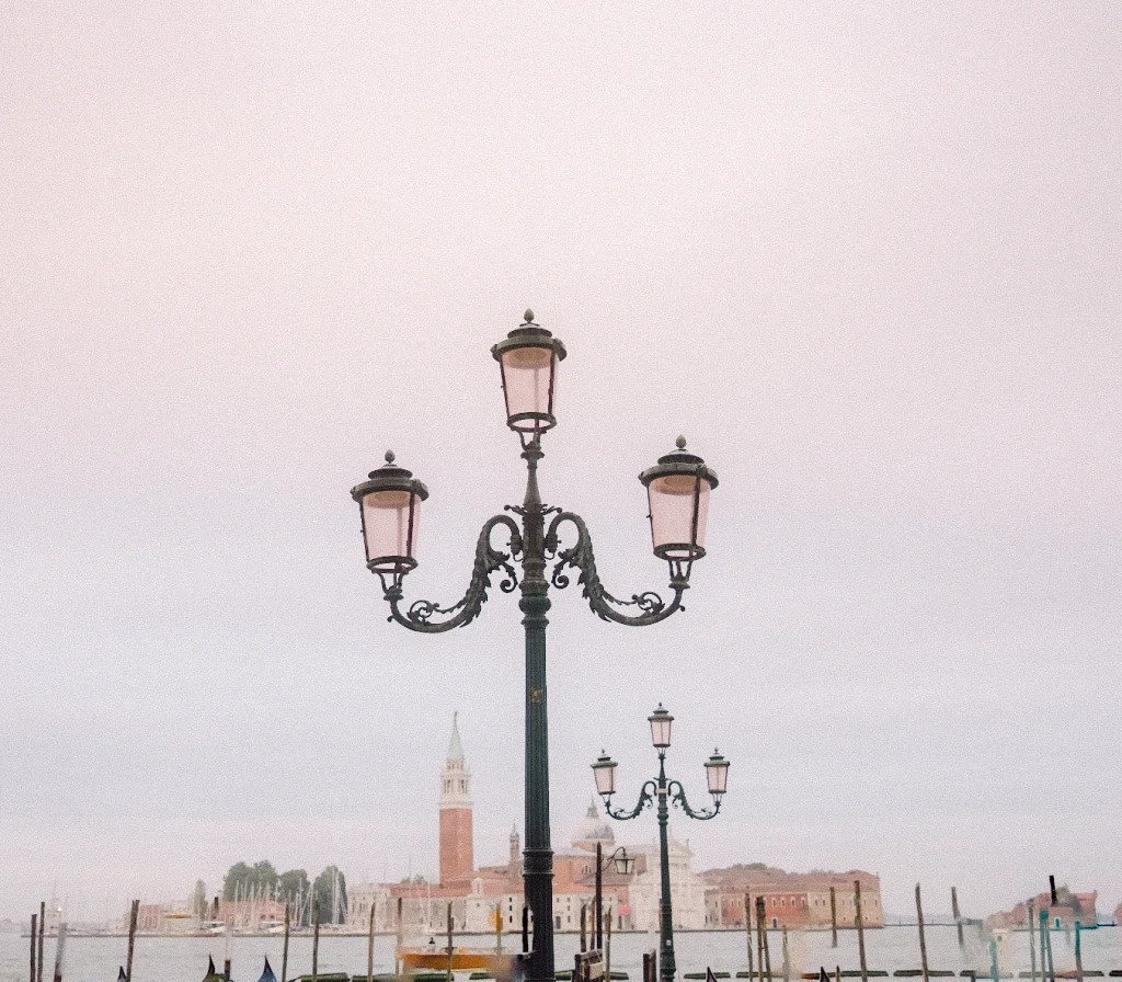 Romantic lamppost at sunset with Venice skyline in the background.